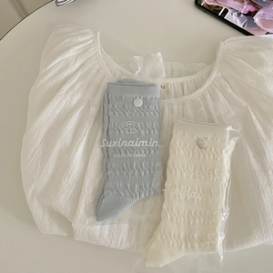 Light blue and cream ribbed crew socks with button detail in minimalist flat lay