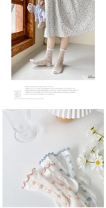 Detail of sheer glass silk socks with delicate floral embroidery and wavy ruffled cuffs