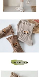 Detail view of knitted crew socks with sunflower embroidery and ruffled lace edge