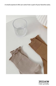 Detail of ribbed knit cotton socks featuring delicate ruffle edges in Morandi tones