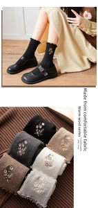 Detail of wool socks with ruffled cuffs and flower embroidery in five earthy colors