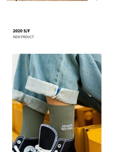 Close-up of olive green ribbed socks with white letter embroidery and denim jeans