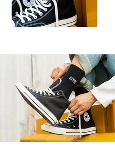 Detail of black cotton crew socks with white letter embroidery paired with canvas shoes