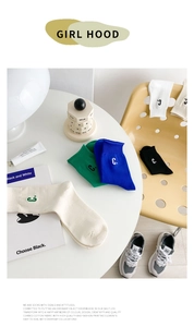 Close-up of cotton mid-calf socks in green, blue and cream with embroidered C logo detail