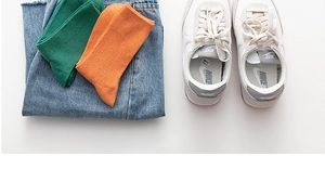 Mise à plat de chaussettes en coton côtelé vert et orange sur un jean denim