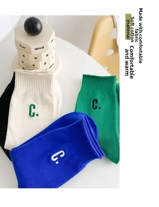 Close-up of four colored cotton mid-calf socks with ribbed cuffs and C embroidery