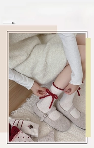 Close-up of white wool socks with red ruffle trim and bow detail worn with Mary Jane shoes