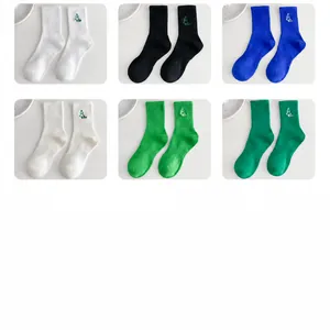 Detail of six mid-calf cotton socks featuring green tree embroidery and ribbed texture