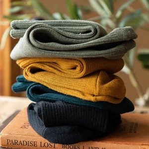 Four pairs of ribbed cotton crew socks in green, yellow and black on vintage books
