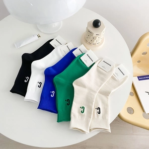 Six pairs of cotton crew socks with 'C' embroidery in assorted colors on a white table