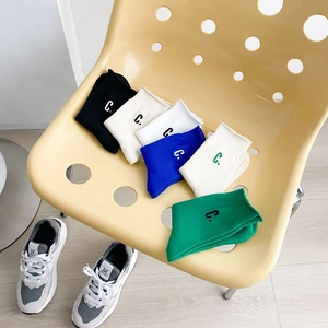 Set of six colorful cotton mid-calf socks with C embroidery on a stylish chair