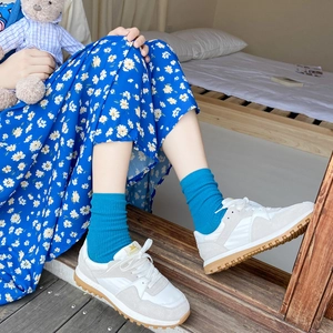 Retro cream sneakers with gum rubber soles paired with blue socks and a floral skirt