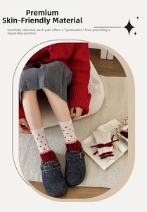 Close-up of red polka dot wool socks paired with grey felt buckled clogs on a cozy rug
