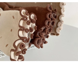 Detailed view of knitted cotton socks featuring cute polka dots and frilly ruffle edges
