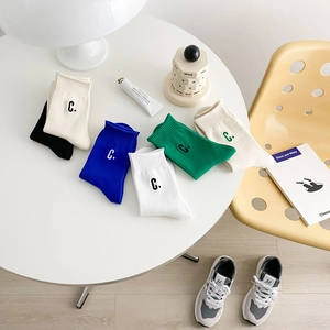 Set of colorful cotton crew socks with C. embroidery on a stylish white table
