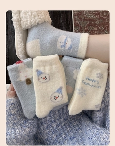Detailed view of thick blue and white thermal socks with cute snowman and tree patterns