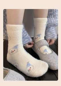 Detailed view of plush white winter socks featuring cute cartoon blue hat snowmen patterns