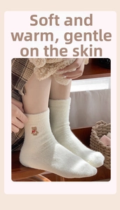 Detail von weichen cremefarbenen Thermosocken mit süßer Bärenstickerei und Plüschtextur