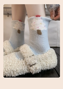 Close-up of light blue winter socks with white Christmas tree pattern and fuzzy shoes