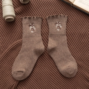 Vintage brown wool socks with flower embroidery and ruffled cuffs on knitted background