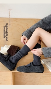Detail of dark grey wool ribbed socks paired with tweed Mary Jane shoes on wood floor