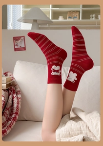 Détail de chaussettes mi-mollet rouges tricotées avec broderie d'ours et rayures
