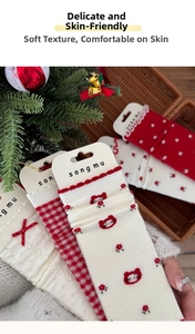 Detailed view of red floral and checkered knitted mid-calf socks with wave edges