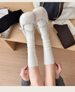 Close-up of off-white faux fur Mary Jane flats with pearl buckles and white wool socks
