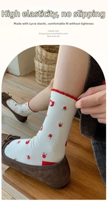 Close-up of white crew socks with red floral patterns and scalloped elastic cuffs