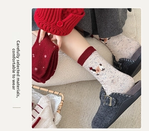 Detail of red floral and beige animal pattern wool socks with ribbed cuffs on model