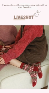 Detail of red wool socks featuring white heart patterns and vintage knit texture