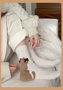 Close-up of cozy cream wool socks featuring a cute cartoon cat pattern and red dots detail