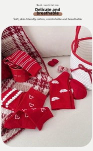Detail of red cotton socks with white stripes and heart patterns in a cozy setting