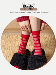 Detail of red crew socks with white stripes and elastic cuff shown with home slippers