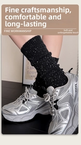 Close-up of black ribbed wool socks with speckled texture worn with silver sneakers