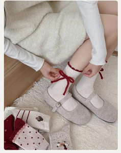 Detailed knit texture of white thermal wool socks with red velvet bow and scalloped edge