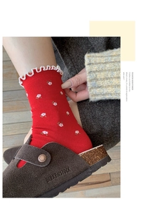 Detail of red floral cotton socks with wavy edges paired with brown leather clogs