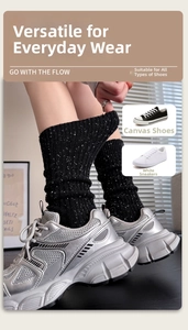 Detail of black wool calf socks with white speckles and ribbed texture in silver sneakers