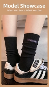 Detail view of black ribbed crew socks featuring a purple sustainable label accent