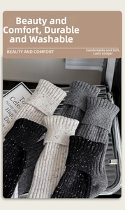 Close-up of thick nep yarn wool socks in white, grey, and black with rolled cuffs
