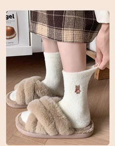 Detailaufnahme der flauschigen Hausschuhe mit weißen Socken und Bärchen-Stickerei