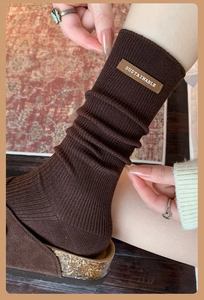 Detail of dark brown ribbed knit socks with leather label and cork sole suede slippers