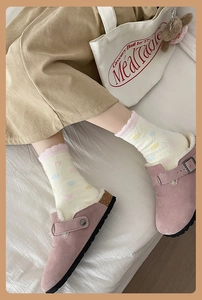 Detail of pink suede clogs with metal buckle and cream plush polka dot warm socks
