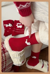 Détail de chaussettes rouges avec écusson de chien en peluche et perle de décoration