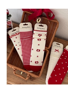 Close-up of red and white knitted crew socks with floral patterns and cartoon cat details