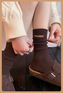 Close-up of brown knit socks with leather sustainable tag and matching suede sandals