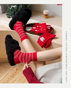 Close-up of red festive socks with cartoon patterns and plush home slippers decoration