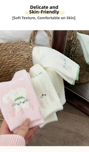 Close-up of soft pink and beige plush cat socks with warm coral fleece texture