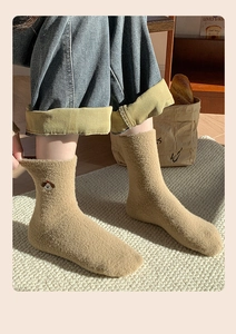 Nahaufnahme dicker khakifarbener Plüschsocken mit Hundestickerei in warmer Winteroptik