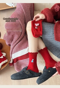 Detail of red knitted crew socks with elegant ruffle cuffs and cute animal embroidery